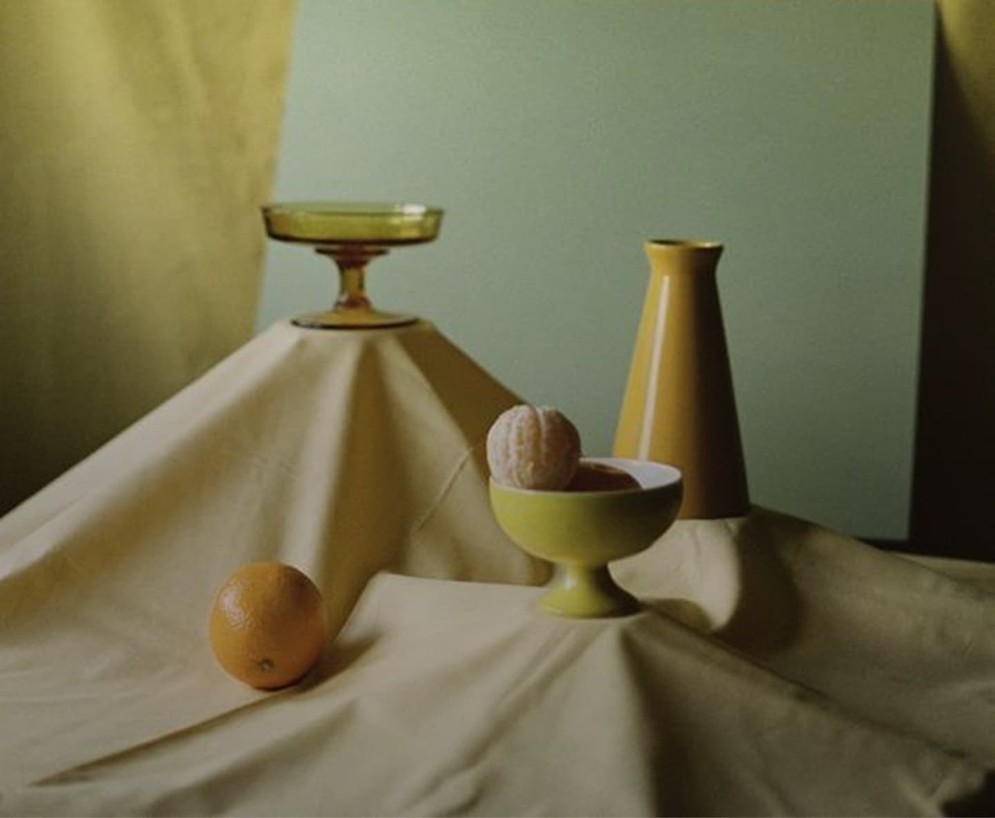 Still life of ceramic vessels and fruit on draped linen